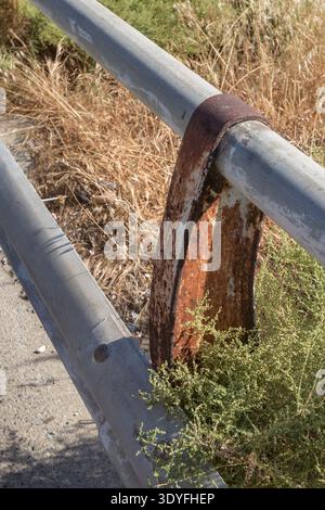 Rusty guardrails on the side of the road. Dry grass and bushes on the side of the road. Stock Photo