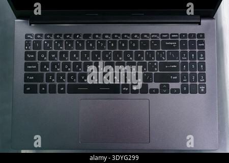 The laptop keyboard is shown from above, highlighting the keys and layout in a simple workspace. The focus is on the keyboard design and arrangement. Stock Photo