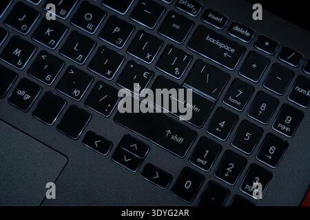 A close view of a computer keyboard shows different keys and their layout. The keys are lit up with low light. Stock Photo