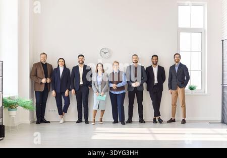 Happy corporate team standing in modern office, diverse colleagues smiling at camera Stock Photo