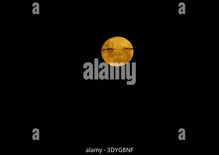 Blood moon during rising before eclipse in dark black sky background. Stock Photo