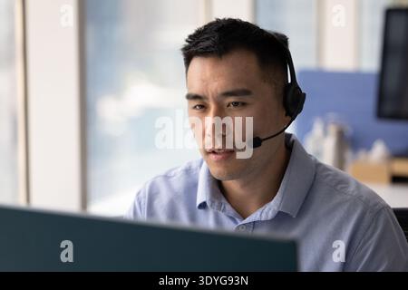 Young man wearing headset speaking by videocall using desktop pc Stock Photo