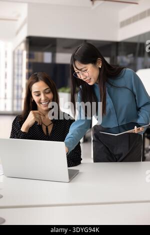 Friendly diverse female coworkers working together at laptop Stock Photo