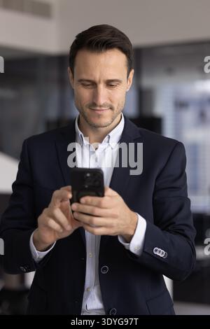 Confident adult man executive messaging on cellphone in work office Stock Photo