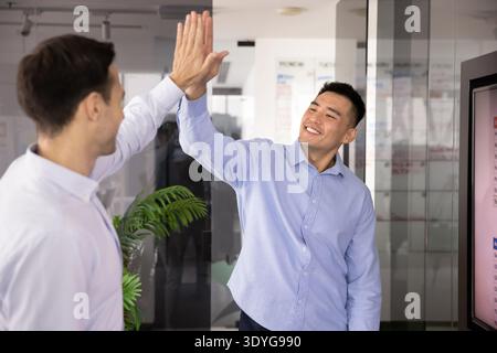 Two excited multiethnic male business professionals giving energetic high five Stock Photo