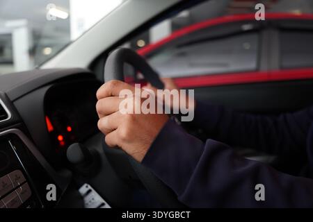 Close-up of a driver's hand shifting gears on a manual or automatic transmission stick. Low-light interior shot of a car center console with climate c Stock Photo