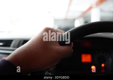 Close-up of a driver's hand shifting gears on a manual or automatic transmission stick. Low-light interior shot of a car center console with climate c Stock Photo