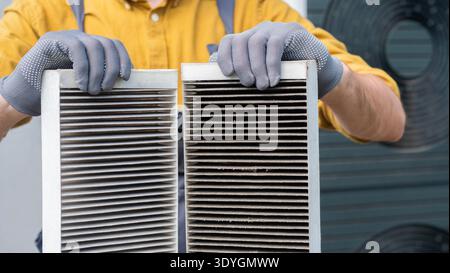 Worker holding two dirty air filters from a home ventilation system. Stock Photo
