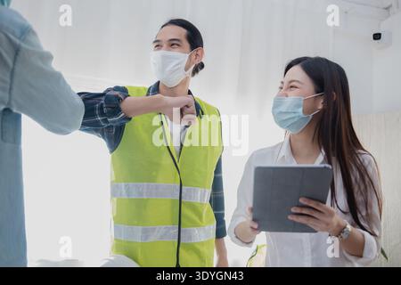 Engineers greeting with elbow bump while wearing face mask during construction meeting Stock Photo