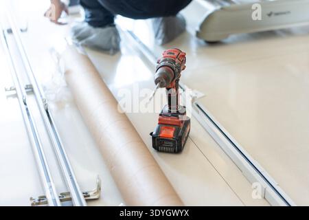 Worker installing window track with cordless drill in modern home interior, Shanghai China Stock Photo