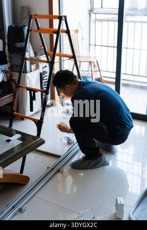 Man installing sliding glass door frame in modern apartment, Shanghai, China Stock Photo