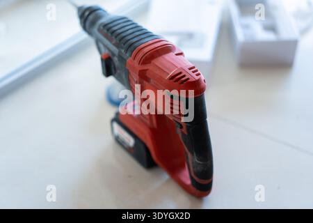 Cordless hammer drill on white workbench in workshop with tool box in background Stock Photo