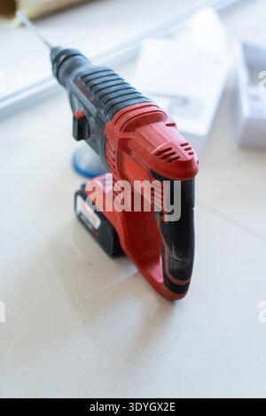 Red and Black Cordless Hammer Drill on White Surface in Workshop Setting Stock Photo