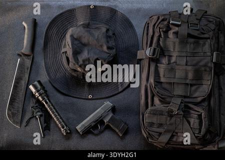 Hiking equipment bag gun knife and flashlight displayed on a black background Stock Photo