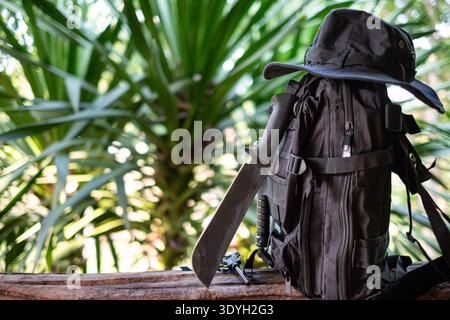 machete knife and a hiking backpack rest on a log. Stock Photo