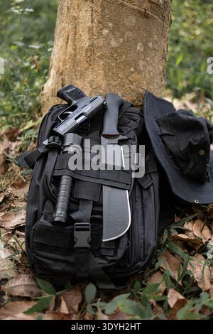 machete knife and a hiking backpack rest on a log. Stock Photo