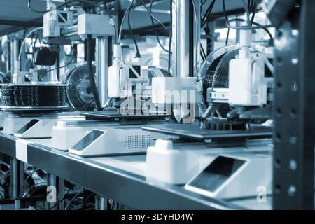3D printer close up. Working 3D printer in process of printing object from molten black plastic. 3D printer creating model by flowing liquid plastic from extruder of printer. 3D printing technology Stock Photo