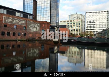 Urban Birmingham canal showing Regency Wharf, moored boats, brick chimney and contemporary glass towers Stock Photo