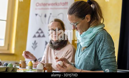 08 March 2026, Brandenburg, Lübbenau: Easter workshop participants begin to apply patterns to hen's eggs. In small groups, people are familiarized with the wax batik or reserve technique at the Easter workshop. In this technique, wax is applied to the areas that are not to be dyed. After the egg has been dyed, the wax is removed again. Photo: Frank Hammerschmidt/dpa Stock Photo