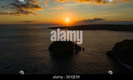 Dramatic evening sky and setting sun over an ocean bay with small rocky islands Stock Photo