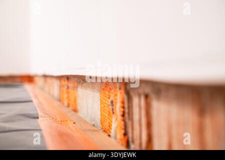 Close-up of a horizontal wall cutout prepared for installing concealed floor baseboard trim with exposed brick and surrounding floor surface. Stock Photo