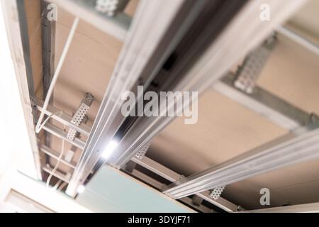 Close-up of a suspended ceiling installation showing metal framework and embedded LED track lighting elements in a modern interior. Stock Photo