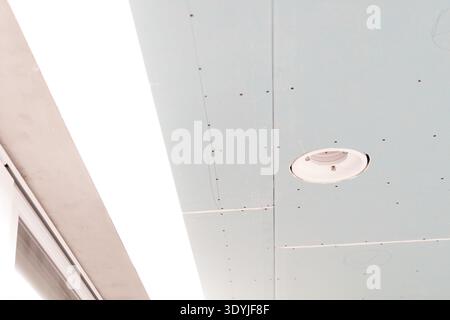 Close-up of a suspended ceiling featuring integrated LED strip lighting and a concealed white circular air diffuser in a modern interior. Stock Photo