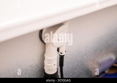 Detailed closeup of a white bathtub drain pipe and plumbing connection under the bathtub rim in a bathroom setting. Stock Photo