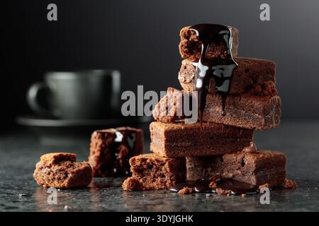 Brownie pieces on a black background. Melted chocolate drips down the brownie. Copy space. Stock Photo