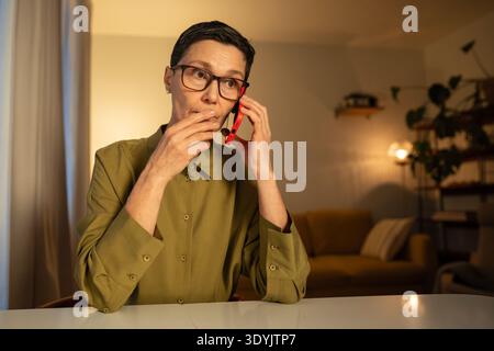 Worried senior woman talking on smartphone with scammers, phone fraud manipulation and misleading. Stock Photo