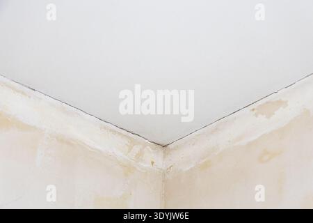 ceiling with cracks in corner of room with peeling wallpaper during city apartment renovation Stock Photo