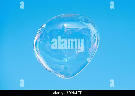 Floating soap bubble reflecting a city and the architecture against a clear blue sky, creating a colorful abstract urban reflection Stock Photo