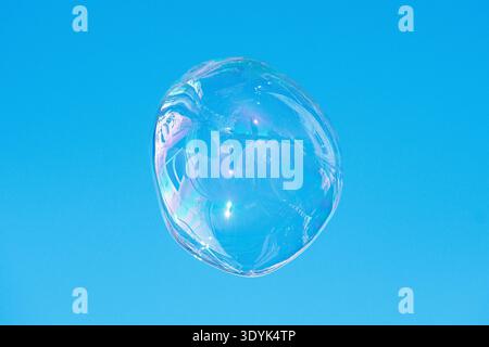 Floating soap bubble reflecting a city and the architecture against a clear blue sky, creating a colorful abstract urban reflection Stock Photo