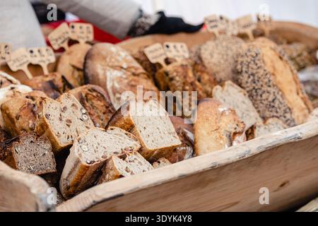 Freshly baked various types of bread displayed in a wooden basket at a bakery or street food market Stock Photo