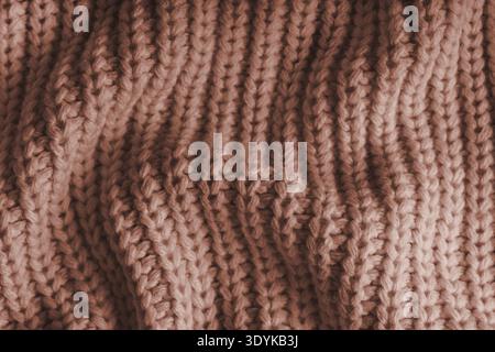 Close up, macro of crumpled brown knitted fabric with visible wrinkles, folds and soft waves. Soft wool texture with detailed stitches and creases, na Stock Photo