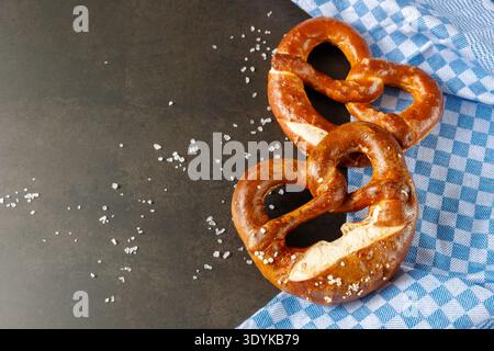 Traditional baked bavarian salty bread pretzels closeup with blue towel on brown rustic stone background. Top view with copy space Stock Photo