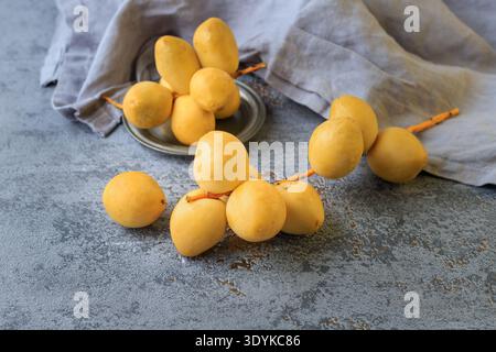 Fresh yellow dates bunches with linen napkin on grey vintage background. Date palm berries or fruits closeup Stock Photo