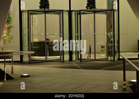 Modern building entrance with revolving doors and Christmas trees Stock Photo