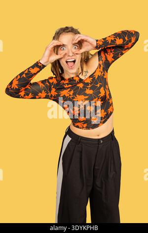 Young woman with dreadlocks smiling and making a binoculars gesture with her hands Stock Photo