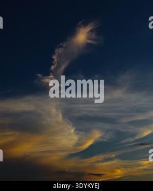 Feather like cloud during evening with orange white colored shade. Stock Photo