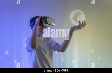 Boy wearing virtual reality headset interacting with holographic digital globe representing global communication, metaverse technology and immersive f Stock Photo