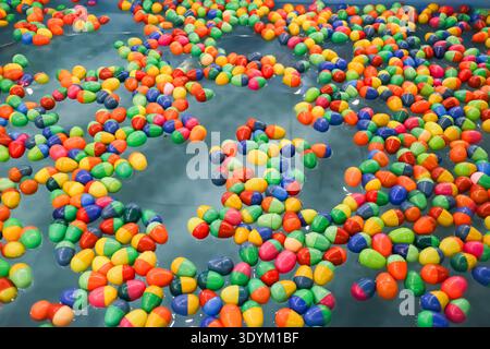 Colorful plastic balls floating on water in a traditional fair game, forming a vibrant abstract background with nostalgic festival atmosphere. Stock Photo