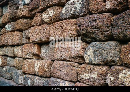 Rustic laterite stone wall background featuring porous blocks and earthy tones. Perfect abstract texture for professional design work. Stock Photo