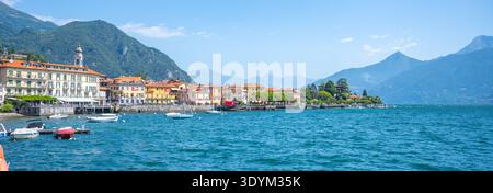 Menaggio showcases its picturesque waterfront, adorned with charming buildings and boats bobbing on the clear blue waters of Lake Como under a vibrant sky. Stock Photo