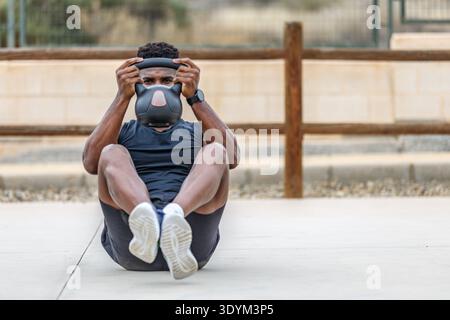 Full body of determined young African American male athlete in sportswear doing abdominal crunches during fitness session on summer day Stock Photo