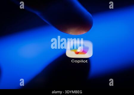 Close-up of a finger touching the Microsoft Copilot app icon on a smartphone screen, representing artificial intelligence integration, mobile producti Stock Photo