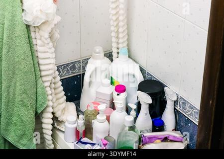 Various white and colored plastic containers of cleaners and cosmetics clustered on a white surface with hanging towels. Stock Photo