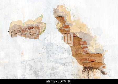 Peeling plaster wall revealing aged brick masonry beneath, cracked paint layers and weathered textures creating an authentic distressed urban backgrou Stock Photo