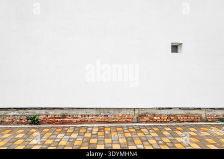 Modern sidewalk with geometric yellow and gray paving blocks against minimal white wall background, clean urban composition with copy space. Stock Photo