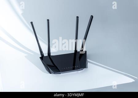 Wireless WiFi router with four antennas on white surface casting shadows representing modern internet networking device Stock Photo